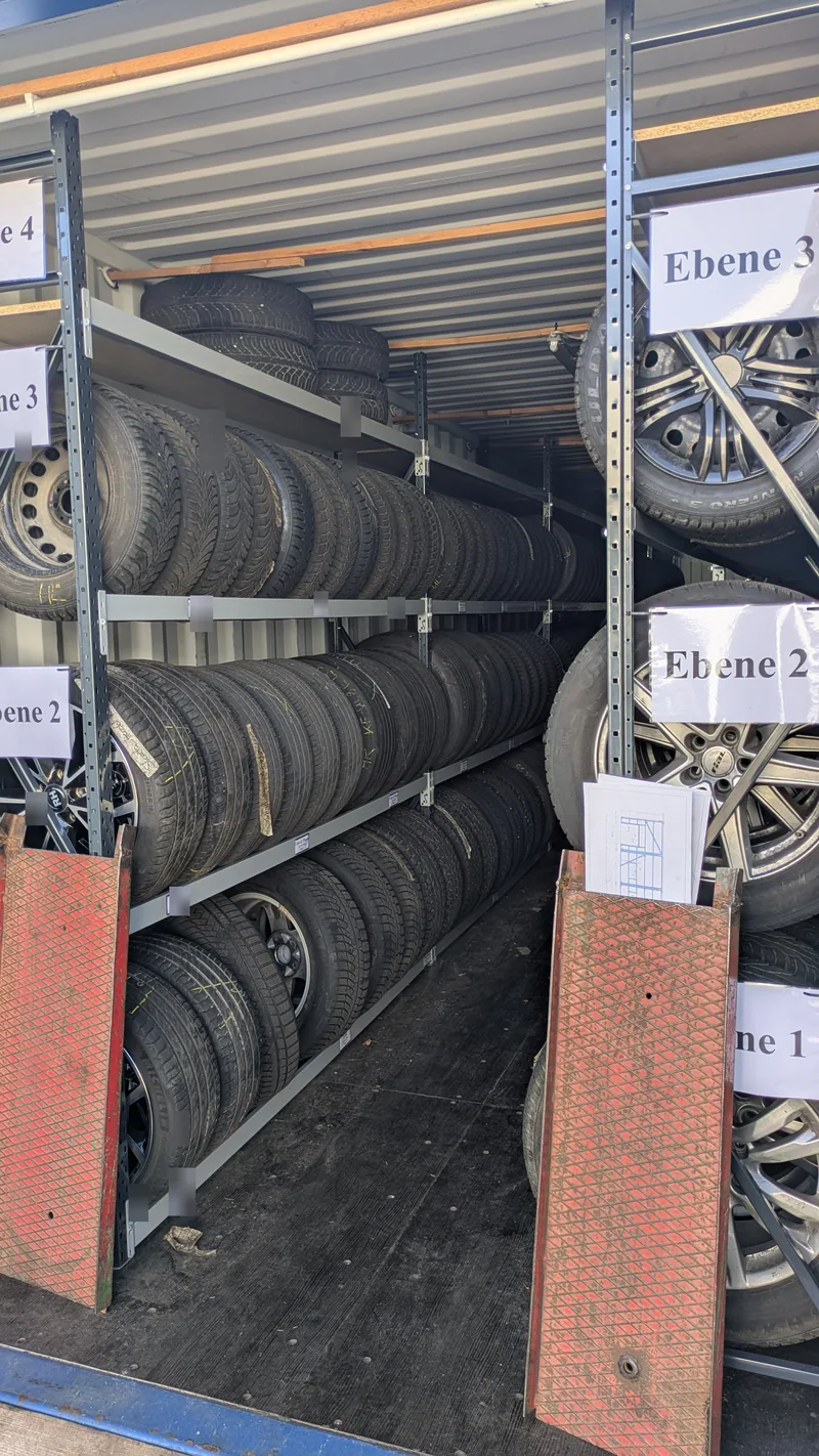 Die vierte Ebene nutzt den verbleibenden Höhenraum Vierte Ebene mit liegenden Reifen auf Einlegebrettern über drei stehenden Räderlagerebenen im Degenhart-Container