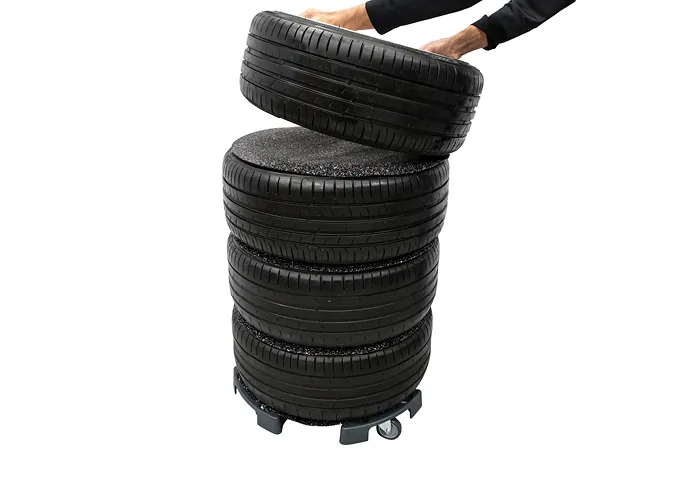 Person setzt ein Komplettrad auf einen mit AHCON Anti-Slip 600 getrennten Radstapel auf dem Wheel Trolley