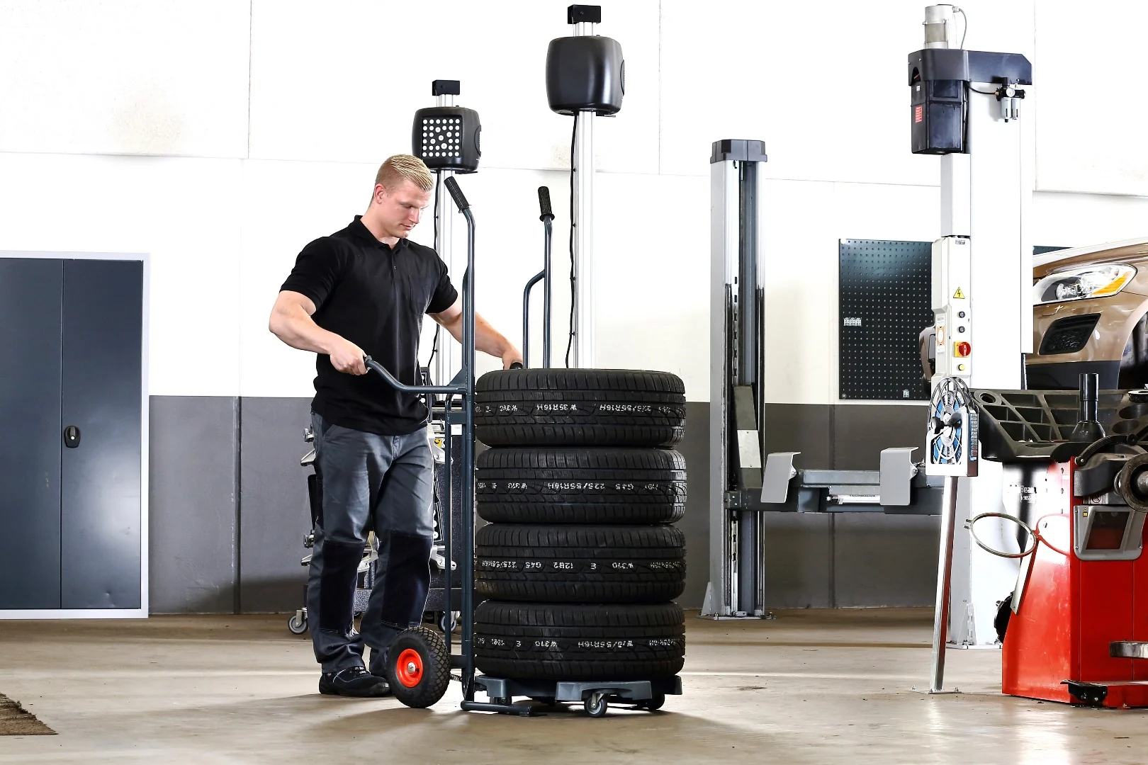 Mitarbeiter schiebt die Gabeln des Wheel Caddy unter den mit Reifen beladenen Wheel Trolley
