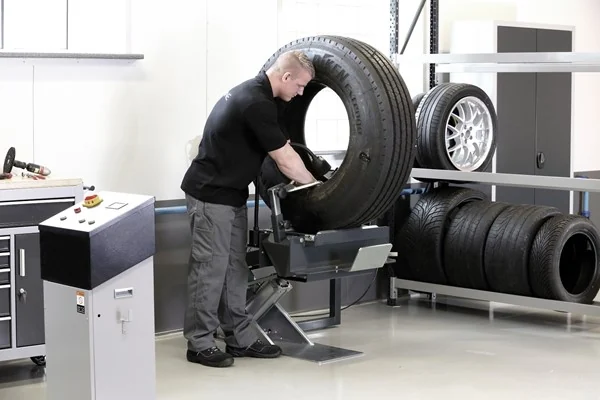 Bediener untersucht die Innenseite eines aufgespreizten LKW-Reifens am TS 9000