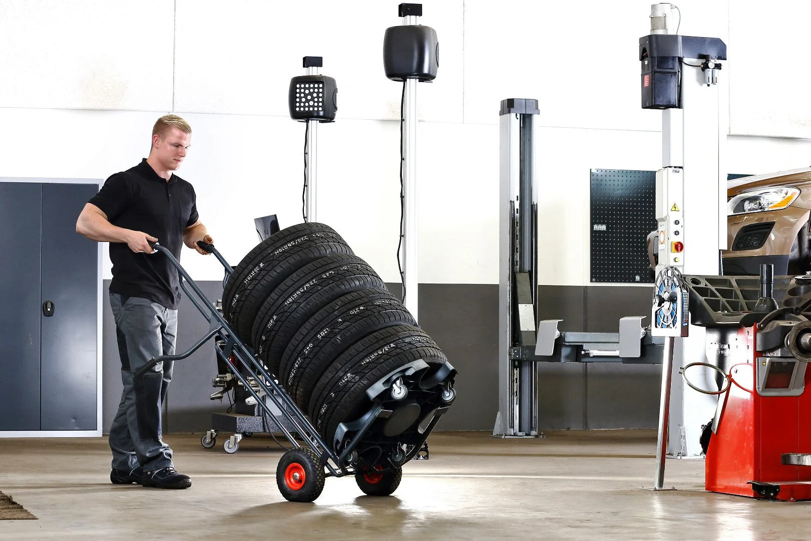 Mitarbeiter neigt einen aufgenommenen Reifenstapel mit dem Wheel Caddy weiter nach hinten