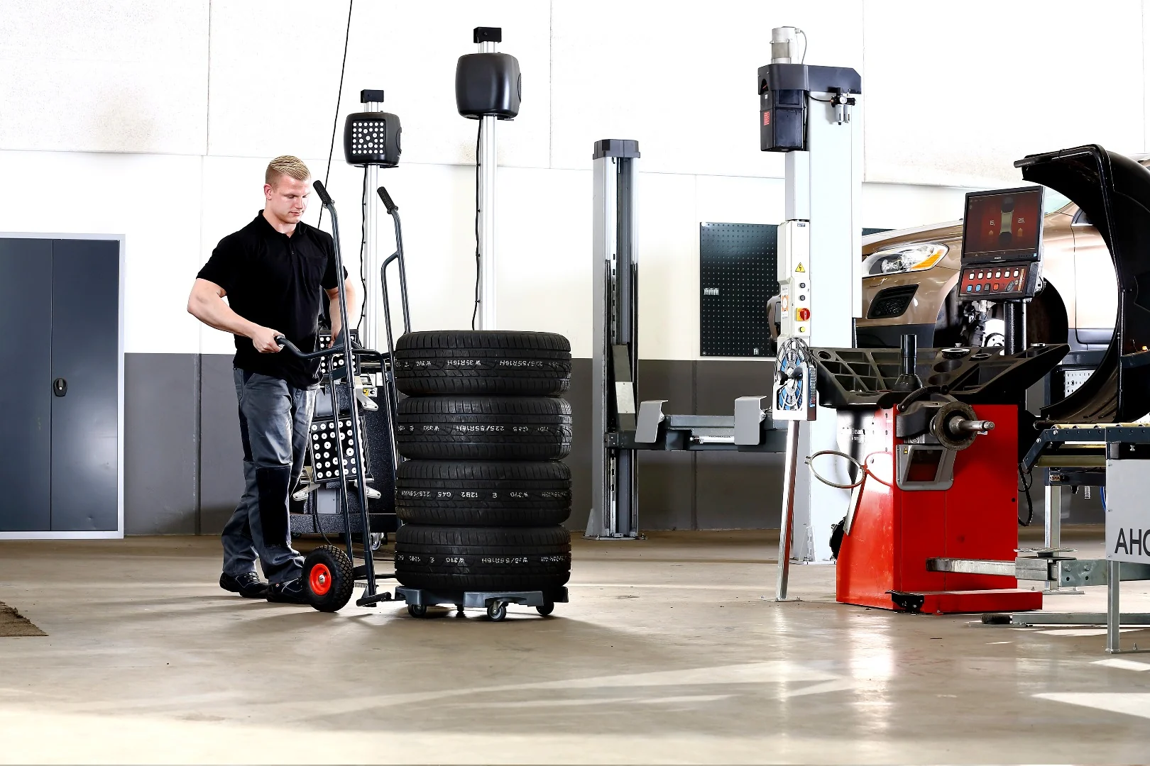 Mitarbeiter richtet den Wheel Caddy hinter einem aufrecht stehenden Reifenstapel aus