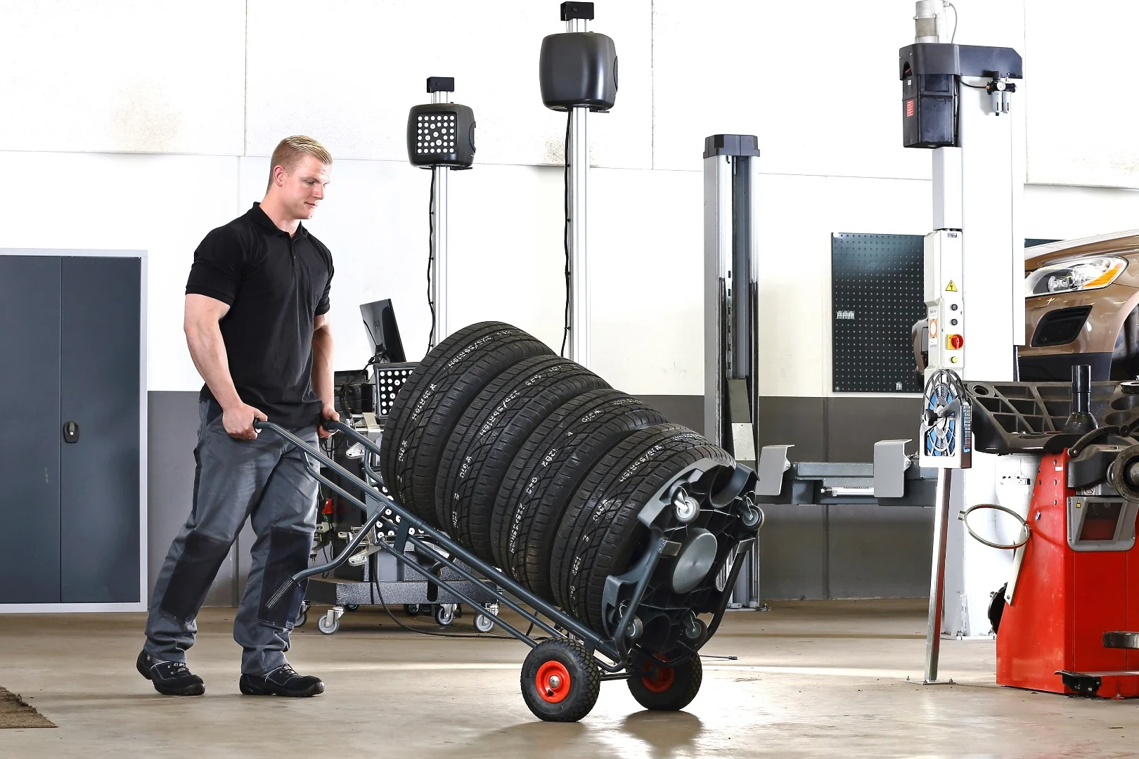 Mitarbeiter transportiert einen Reifenstapel in flacher Neigung mit dem Wheel Caddy